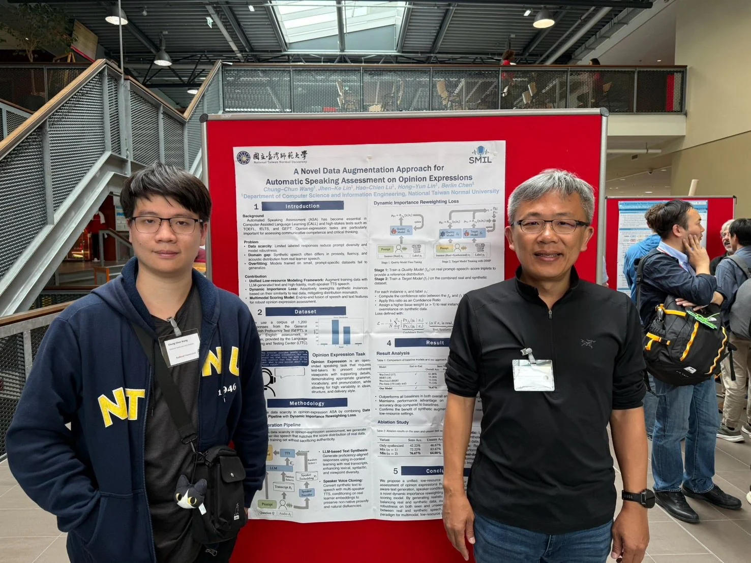 SLaTE 2025 論文發表貼文中的雙人合照,身後海報題名為「A Novel Data Augmentation Approach for Automatic Speaking Assessment on Opinion Expressions」。